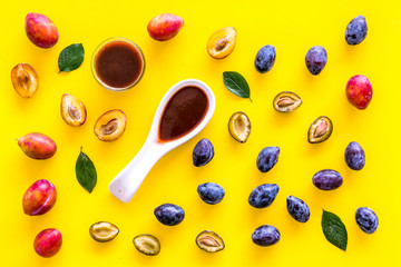 Fresh tkemali sauce. Traditional caucasian, georgian sauce or plum jam in spoon near plums on yellow background top view