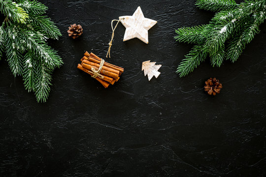 New year symbols. Spruce branch, cones and toys for decoration like spruce and stras on black background top view copy space