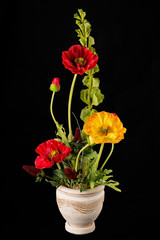Floral arrangement from artificial poppy flowers in old ceramic flower pot.