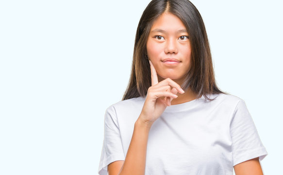 Young asian woman over isolated background with hand on chin thinking about question, pensive expression. Smiling with thoughtful face. Doubt concept.