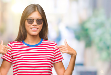 Young asian woman wearing sunglasses over isolated background looking confident with smile on face, pointing oneself with fingers proud and happy.