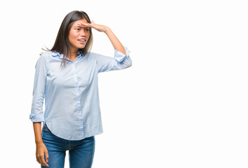 Fototapeta premium Young asian business woman over isolated background very happy and smiling looking far away with hand over head. Searching concept.