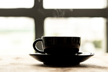 smoke of black coffee in the black cup on the black plate 