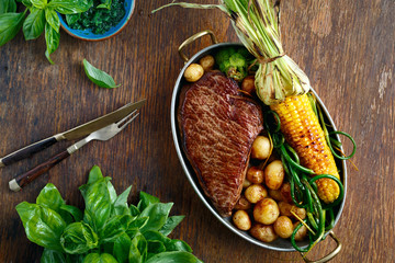 Beef steak served frying pan fried potatoes vegetables top view