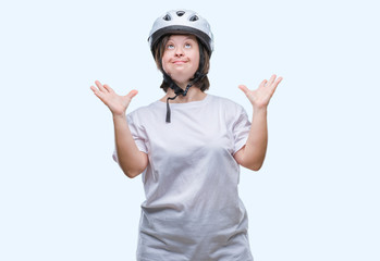 Young adult cyclist woman with down syndrome wearing safety helmet over isolated background crazy and mad shouting and yelling with aggressive expression and arms raised. Frustration concept.