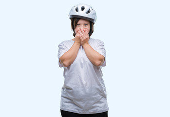 Young adult cyclist woman with down syndrome wearing safety helmet over isolated background shocked covering mouth with hands for mistake. Secret concept.