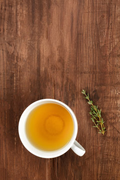 An overhead closeup photo of tea on a dark rustic background with a thyme branch and copy space