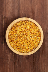 Healthy organic food. Bee pollen, shot from above in a wooden bowl on a dark rustic background with a place for text