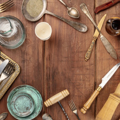 A photo of many vintage kitchen objects and cutlery from an old restaurant, flea market stuff, shot from the top on a wooden background with a place for text