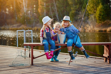 Children fishing with fishing rods. Warm autumn day. Fishing on a wooden pontoon