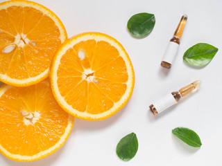 Vitamin C brown ampule for injection with fresh juicy orange fruit slices on white table. High dose...