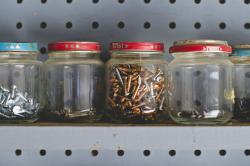 A long row of little glass storage jars full of screws