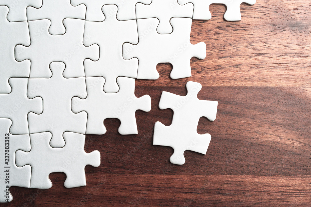 Aufkleber unfinished white jigsaw puzzle pieces on wood table.assembling jigsaw puzzle pieces. abstract backgr