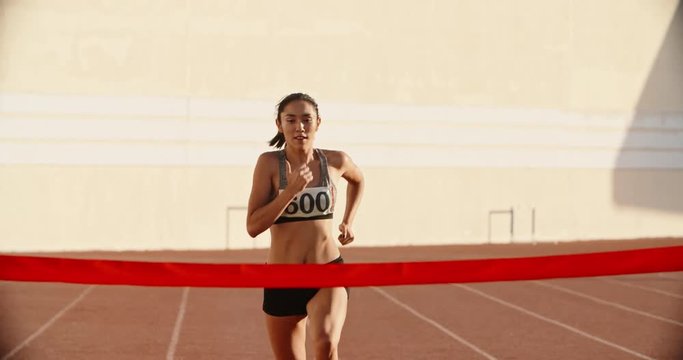 Female athlete on track. Young asian runner runing on track of stadium, jumping over barriers, then crossing the finish line preparing for competition 4k