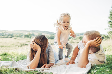 Young Adult Couple with Their Little Daughter Having Fun in the Park Outside the City, Family Weekend Picnic Concept, Three People Enjoying Summer Time