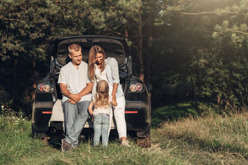 Young Adult Couple with Their Little Daughter Having Fun in the Park Outside the City, Family Weekend Picnic Concept, Three People Enjoying Summer Time