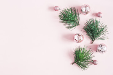 Christmas composition. Frame made of pink disco balls and pine branches on pastel pink background. Christmas, winter, new year concept. Flat lay, top view, copy space