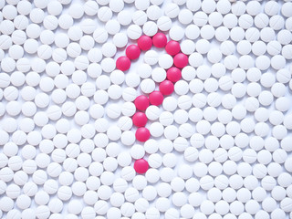 Question mark formed by unique pink pills among white ones background. Creative medicine for health/medical problem, drug information services, medication error and pharmacy concept.