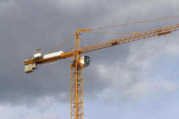 Yellow tower crane on the background of rain clouds
