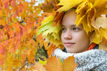 beautiful girl hid in maple leaves on the background of autumn