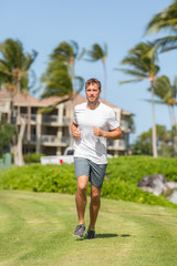 Healthy young man runner working out jogging happy on grass summer outdoors. Fit and active lifestyle.