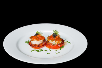 Scallops, tomatoes and ketchup on white plate, black background