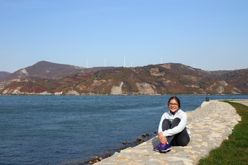 Fototapeta premium beautiful happy teenage girl is sitting by the river
