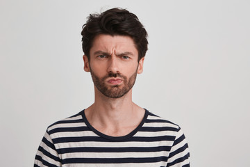 Clouse up of young brown hair man with beard looks displeased, eyebrows furrowed, his mouth twisted...
