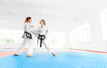 Young karate girl helping to her partner stretching leg before training. © serhiibobyk