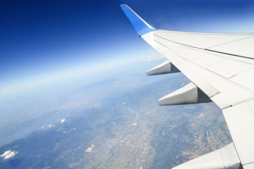 Beautiful view of earth and sea under the wing of plane. The image is rotated diagonally. The...