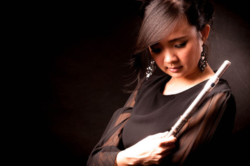 Fashion portrait in studio of beautiful young woman feeling happy with her flute against dark background in studio