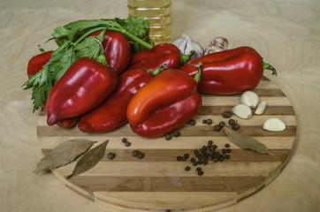 Red bell peppers,celery, garlic and spices on a wooden chopping Board with a bottle  of olive oil on a wooden table
