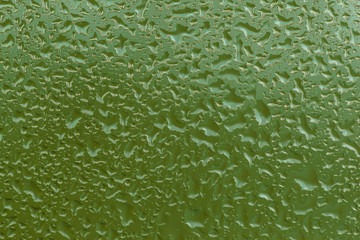 Rain drops on window with green background