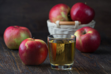 Glass of apple juice with red apples on wooden table, closeup