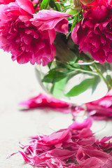 red peonies in glass vase stand on table