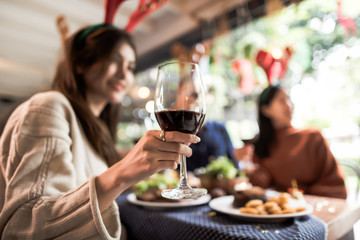 Dinner with friends. Group of young people enjoying dinner together. Focus on a glass of wine.