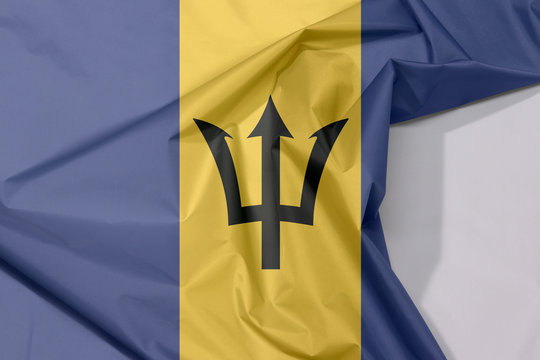 Barbados fabric flag crepe and crease with white space, triband of ultramarine (hoist-side and fly-side) and gold with the black trident-head centred on the gold band.