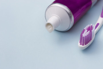 Toothpaste in tube and toothbrush on blue background. Dental hygiene concept.