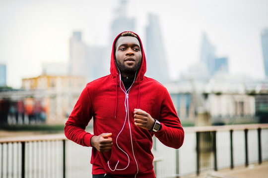 Young sporty black man runner running on the bridge outside in a city.