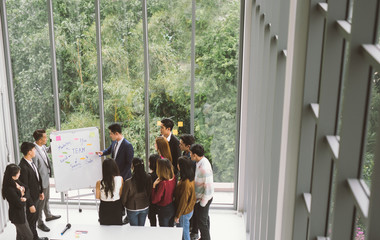 Businessman presenting at whiteboard Gruop of business people standing around white board during meeting in office