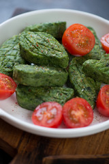 Close-up of roasted spinach nuggets with cherry tomatoes, selective focus, vertical shot