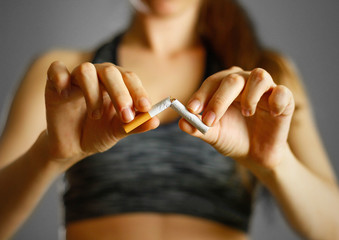 Sporty girl holding a broken cigarette in her hand. Close up. Isolated background