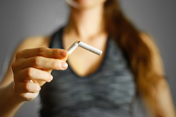 Sporty girl holding a broken cigarette in her hand. Close up. Isolated background