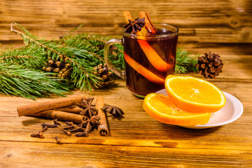 Cup of mulled wine with cinnamon, sliced orange and fir tree branches on wooden table