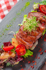 Tasty sliced roast duck breast with fresh vegetable salad closeup on a plate.
