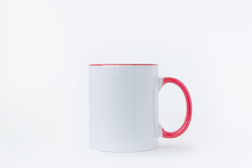 A white mug, with a red handle on a light background. 