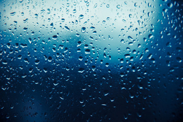 Raindrop on glass window, blue drops.