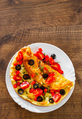 omelette with tomato, pepper and olive in white plate on wooden table background