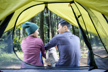 Rear view of asian couple relaxing outside the tent