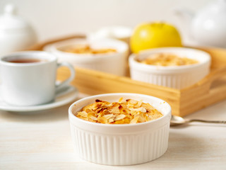 Cheesecake on white wooden table in kitchen. Delicate curd dessert with apples, almond flakes and cinnamon, side view